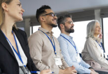 People sitting in a row wearing lanyards at a conference