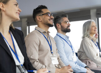 People sitting in a row wearing lanyards at a conference