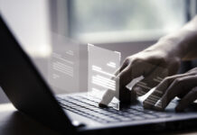 Hand using laptop computer with virtual screen and document