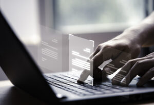 Hand using laptop computer with virtual screen and document