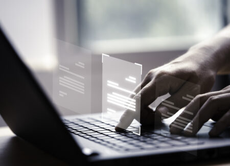 Hand using laptop computer with virtual screen and document